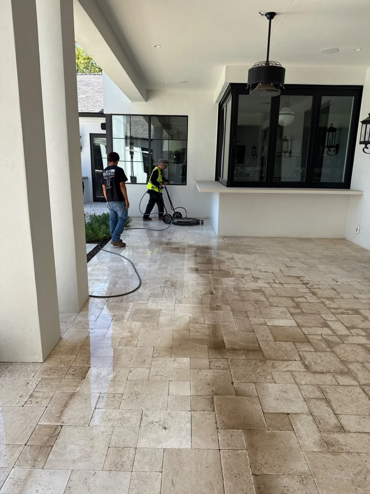 Two Clean Surface crew members surface-cleaning a covered residential patio