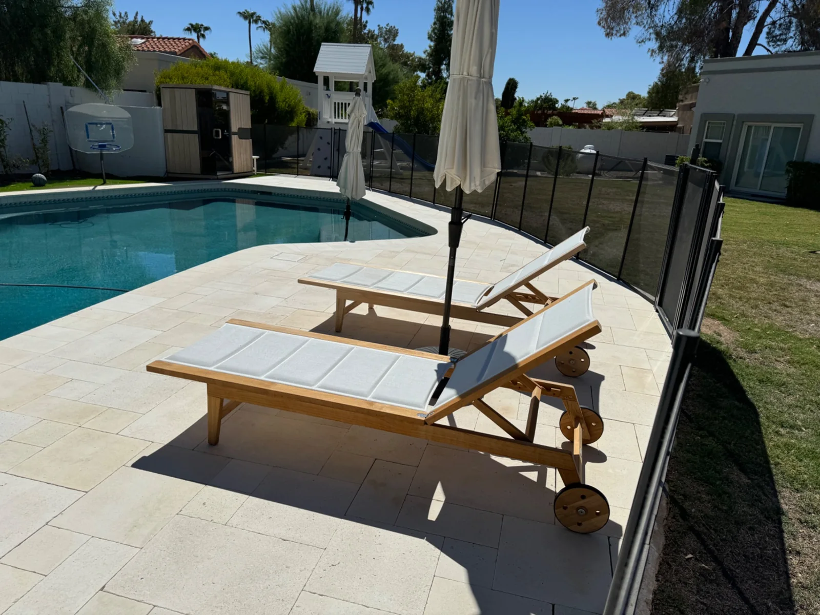 Stone pool deck with two loungers beside an Arizona pool